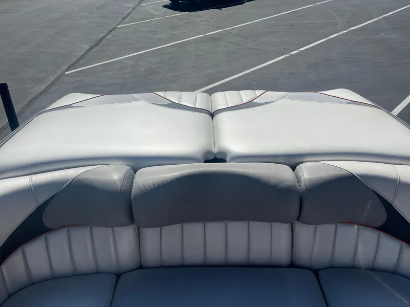 Slide: The Image of 2015 MB B52 23 boat interior with white cushioned seating in a parking lot. - 7