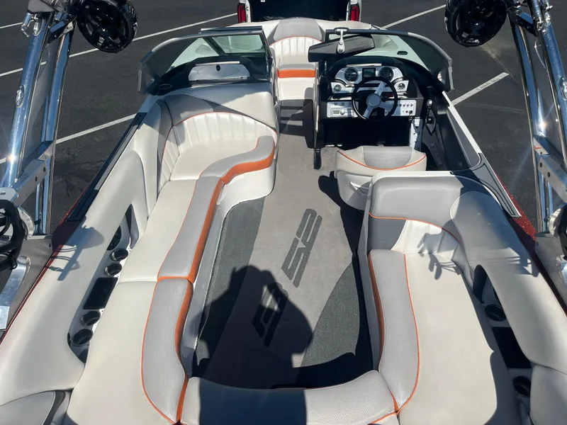 Slide: The Image of 2015 MB B52 23 boat interior with white and orange seating, sleek dashboard, and spacious layout. - 8