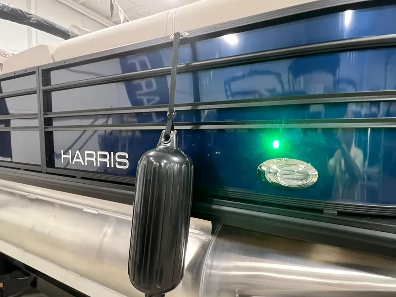 Slide: The Image of 2024 Harris Sunliner 230 pontoon boat with blue exterior and black fender. - 21