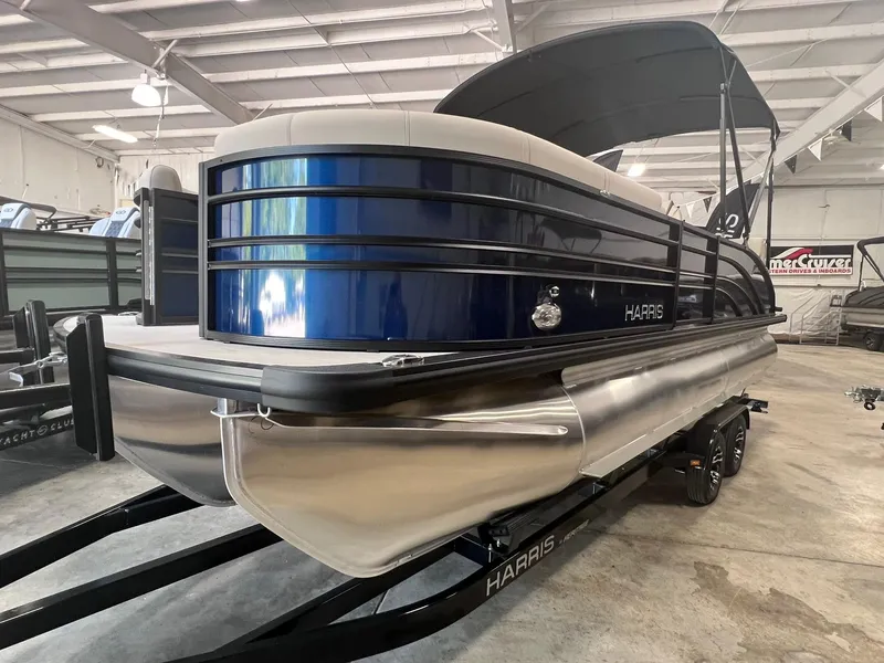 Slide: The Image of 2024 Harris Sunliner 230 pontoon boat in showroom, featuring sleek blue and silver design. - 3