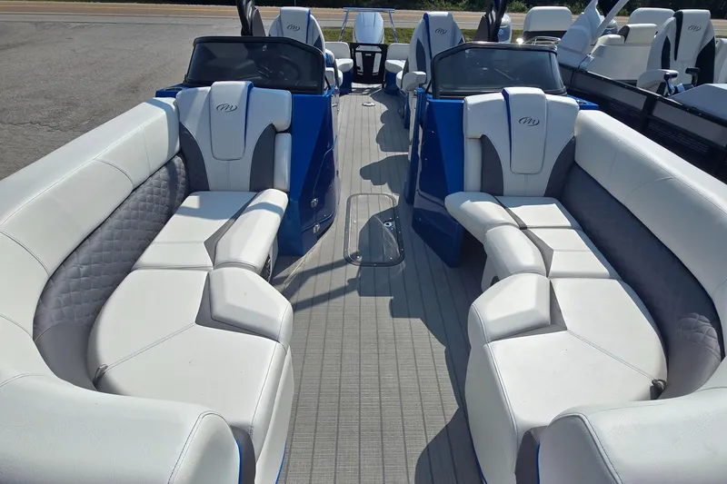 Slide: The Image of 2025 Manitou 25' LX RFXW pontoon boat with luxurious white seating and blue accents. - 12