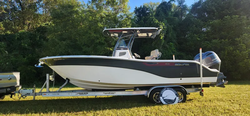 Slide: The Image of 2019 Sea Fox 266 Commander boat on trailer, parked on grass with trees in background. - 0