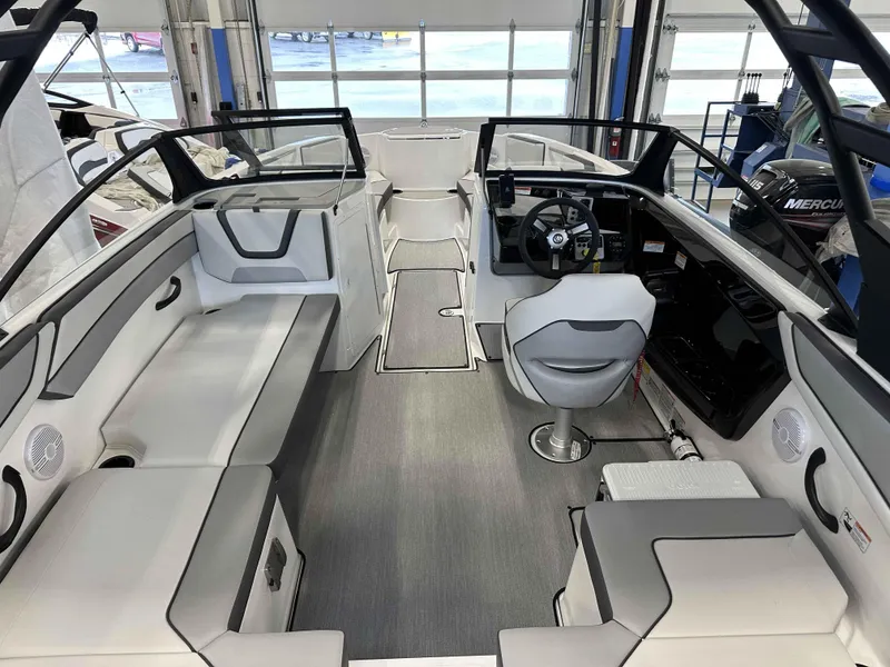 Slide: The Image of 2025 Yamaha Boats AR220 interior with modern seating and steering wheel in a showroom. - 4