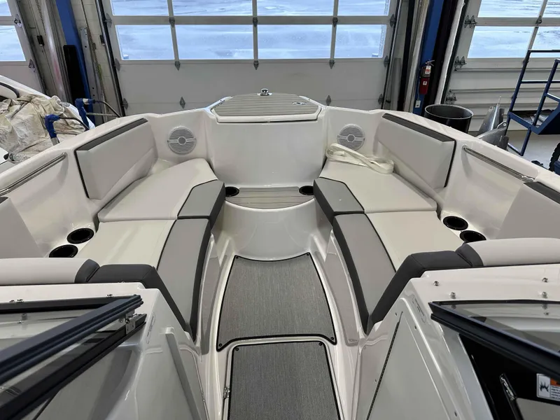 Slide: The Image of 2025 Yamaha Boats AR220 interior with gray seating and cup holders in a garage setting. - 8