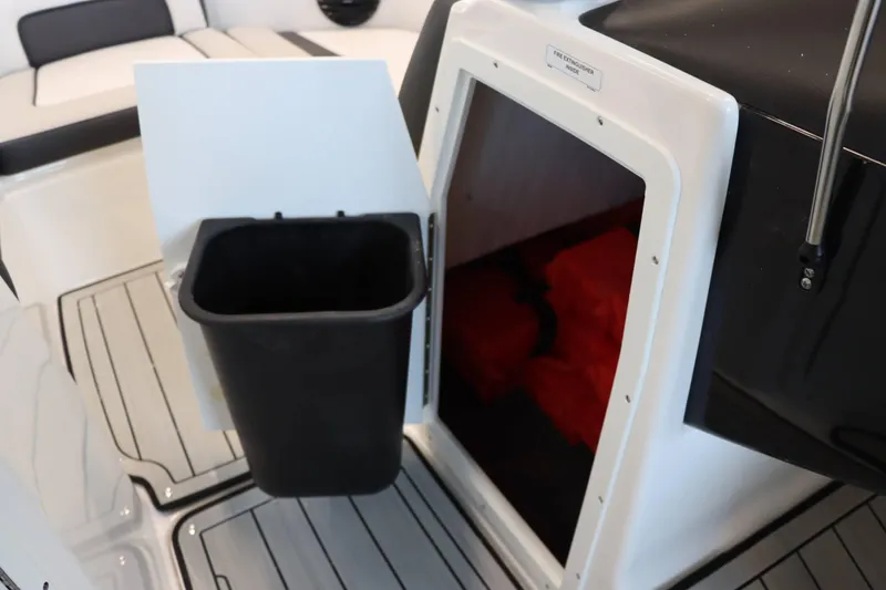 Slide: The Image of 2025 Yamaha Boats 195S interior storage compartment with trash bin and safety equipment. - 17