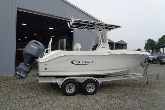 Slide: The Image of 2025 Robalo R202 Explorer boat on trailer, parked outside a large building. - 24