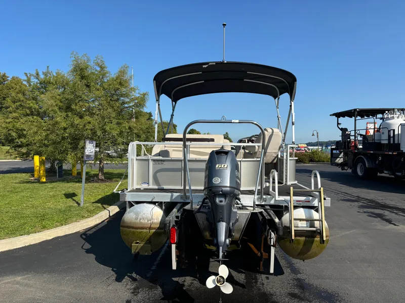 Slide: The Image of 2014 Bennington 24 SSLX pontoon boat with canopy and outboard motor, parked on pavement. - 12