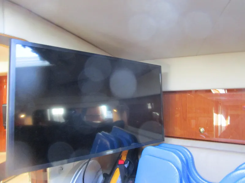 Slide: The Image of Interior of 2001 Sea Ray 340 Amberjack with mounted TV and blue chairs. - 18