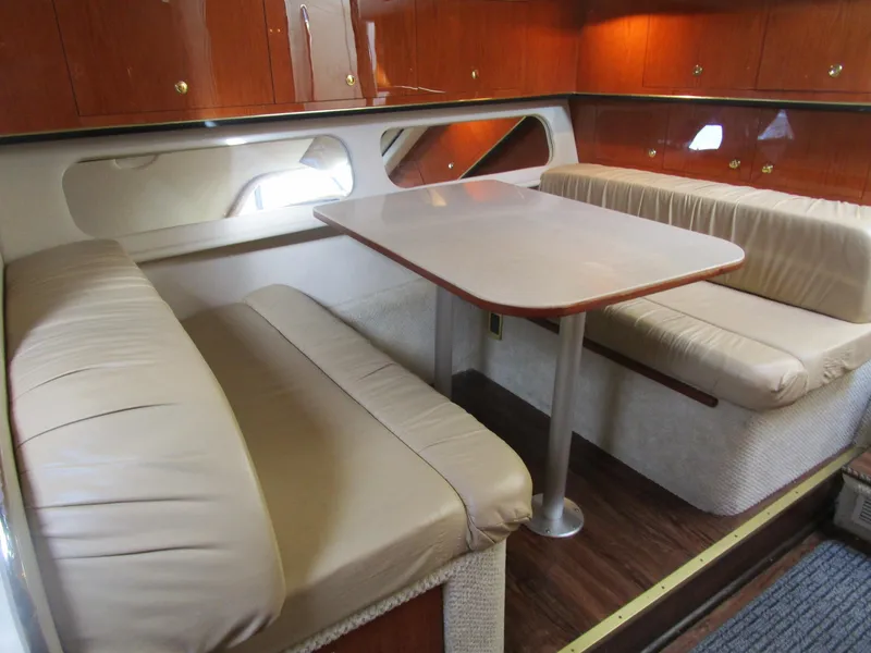 Slide: The Image of 2001 Sea Ray 340 Amberjack cabin with dining area, beige seating, and wooden cabinetry. - 19