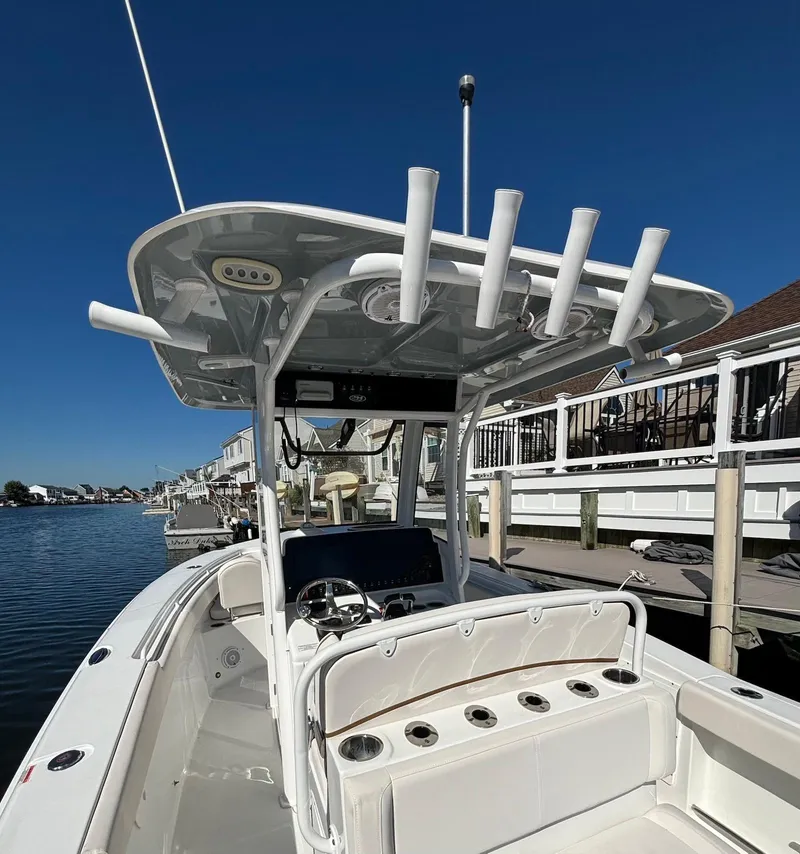 Slide: The Image of 2020 Sea Hunt Ultra 275 SE boat docked, featuring rod holders and a spacious deck. - 12