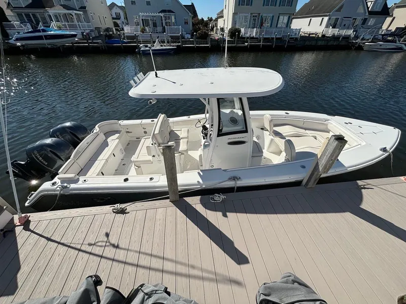 Slide: The Image of 2020 Sea Hunt Ultra 275 SE boat docked in a marina, featuring dual engines. - 2