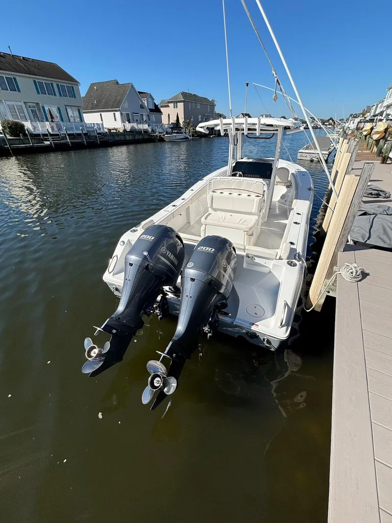 Slide: The Image of 2020 Sea Hunt Ultra 275 SE boat docked with dual engines, in a residential canal setting. - 20