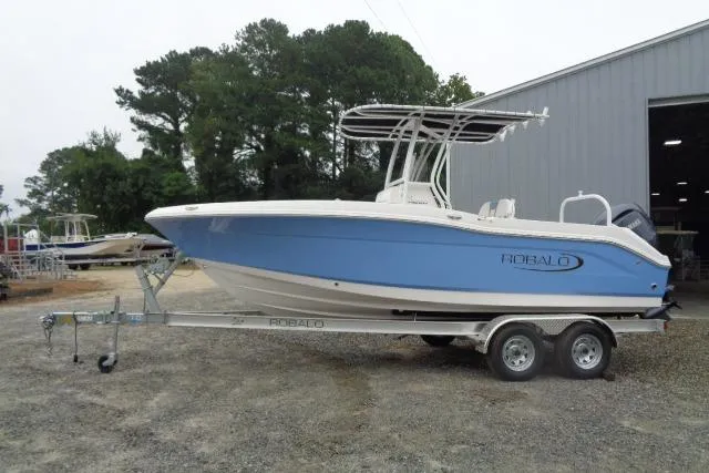 The Image of 2025 Robalo R200 Center Console boat on trailer, blue and white design, parked outdoors. - 11