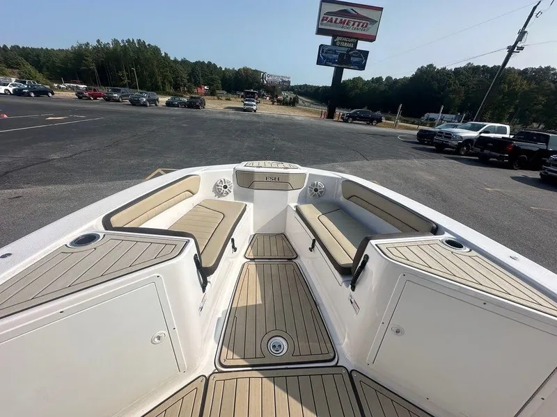 Slide: The Image of 2022 Yamaha Boats 210 FSH® SPORT interior with seating and storage, parked outdoors. - 4