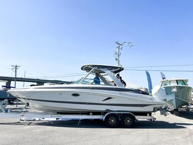 Slide: The Image of 2025 Crownline 290 XSS boat on trailer, displayed outdoors under clear blue sky. - 2