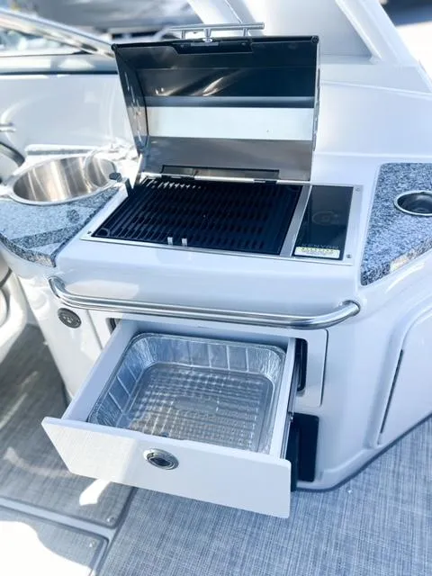 Slide: The Image of Outdoor grill and sink on 2025 Crownline 290 XSS boat, featuring storage drawer. - 23