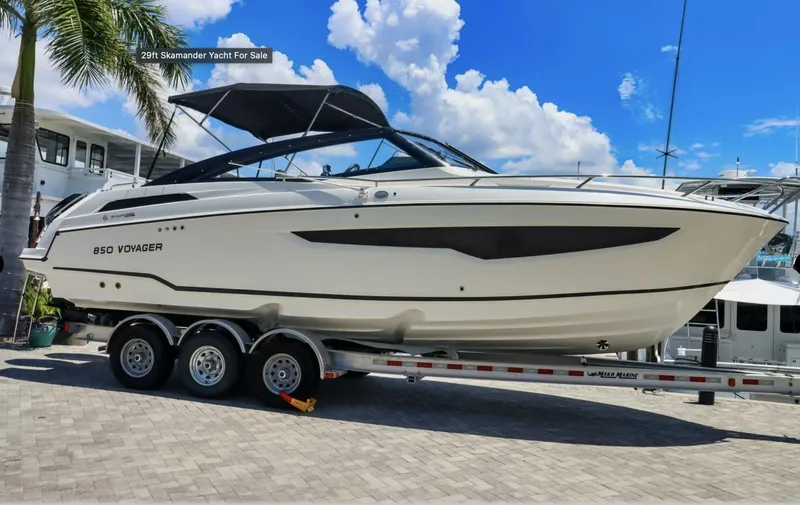 Slide: The Image of 2024 Skamander 850 Voyager yacht on trailer, displayed outdoors under blue sky. - 21