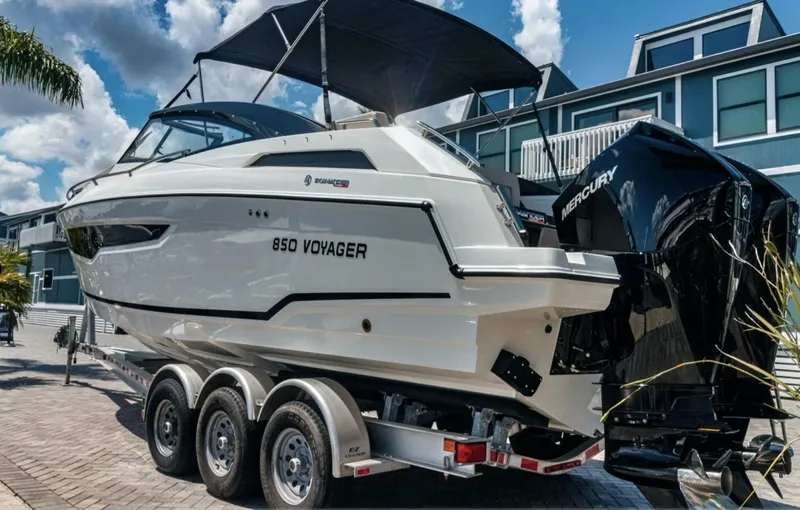 Slide: The Image of 2024 Skamander 850 Voyager boat on trailer, parked near modern buildings. - 3