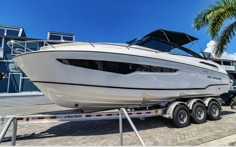 Slide: The Image of 2024 Skamander 850 Voyager boat on trailer, sleek design, sunny day, palm tree background. - 4