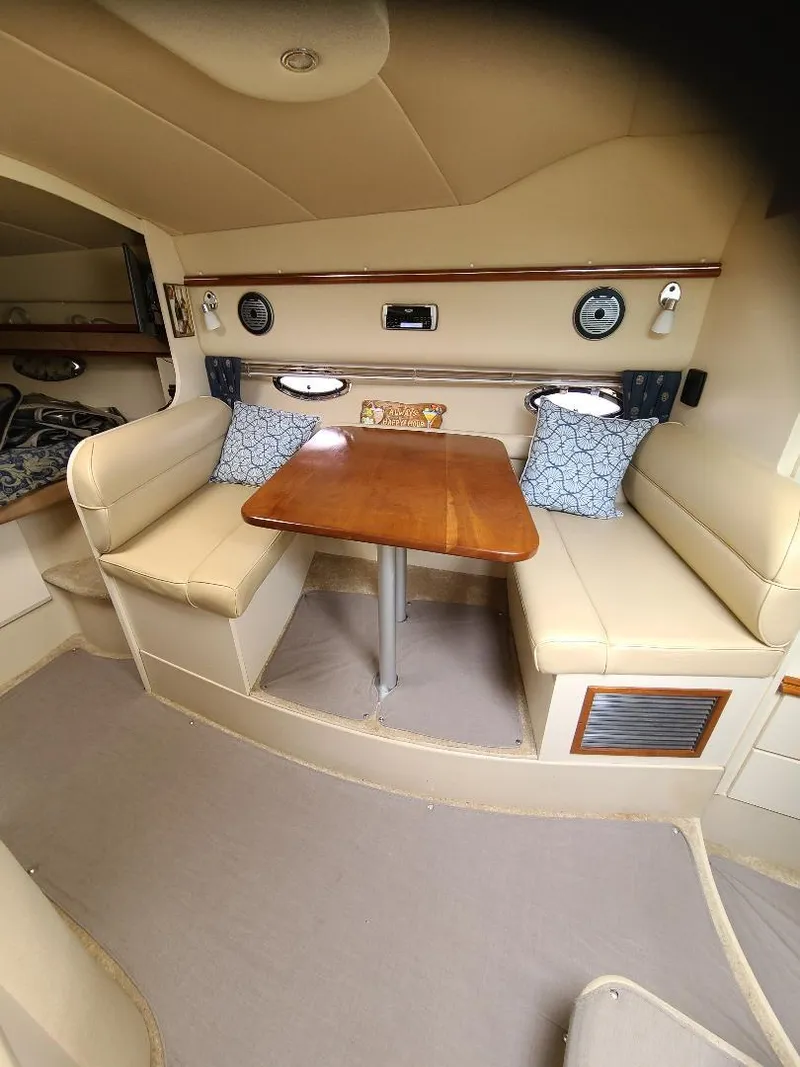 Slide: The Image of 2004 Cruisers 3372 yacht interior with dining area, cushioned seating, and wooden table. - 18