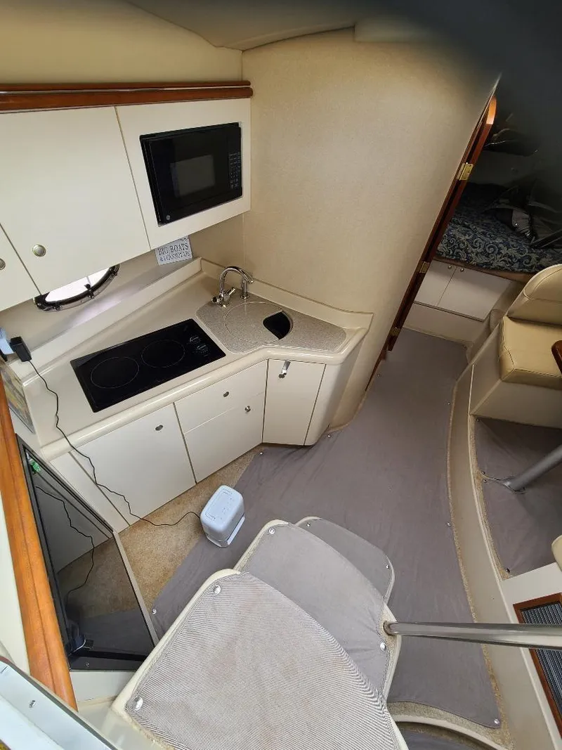 Slide: The Image of 2004 Cruisers 3372 yacht interior with kitchenette, featuring stove, microwave, and sink. - 20