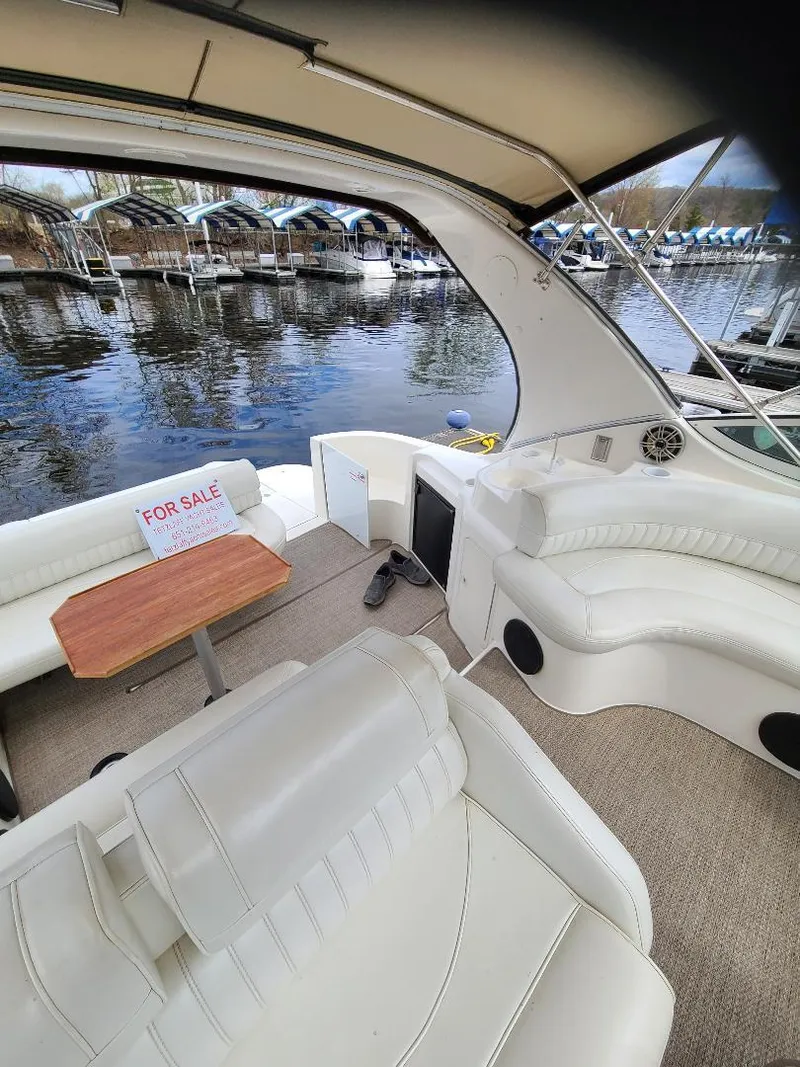 Slide: The Image of 2004 Cruisers 3372 yacht interior with white seating, wooden table, and "For Sale" sign. - 23