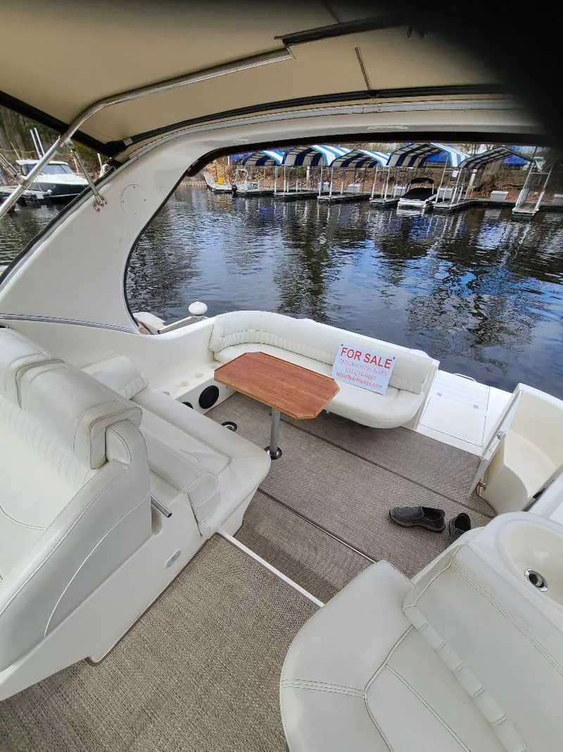 Slide: The Image of 2004 Cruisers 3372 yacht interior with seating, table, and "For Sale" sign by the water. - 25