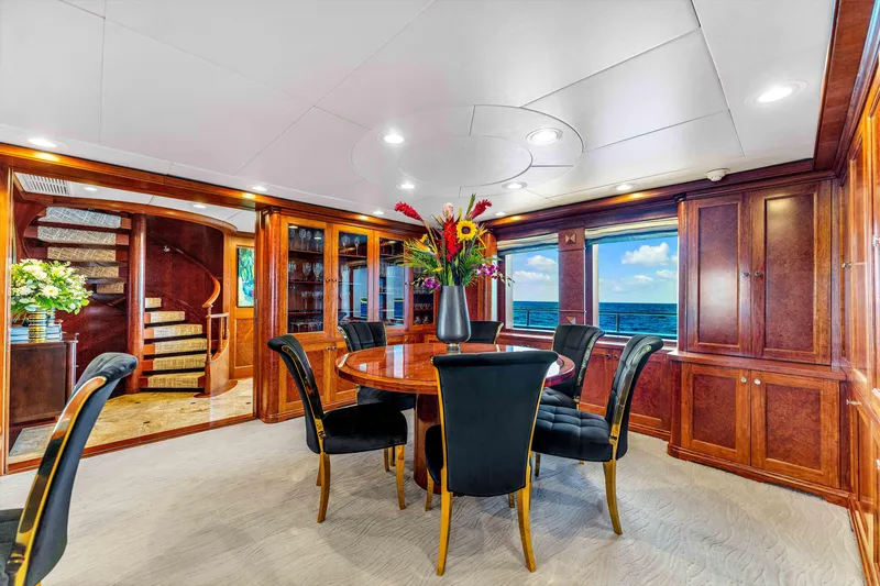 Slide: The Image of Luxurious dining area on 1998 Admiral Pilothouse yacht with elegant wood paneling and floral centerpiece. - 13