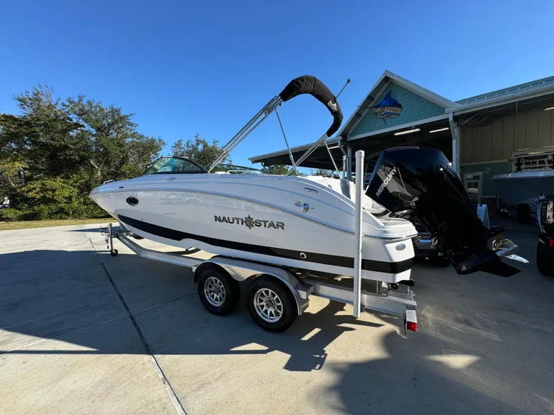 Slide: The Image of 2025 NauticStar 243 DC Deck boat on trailer, parked outdoors. - 10