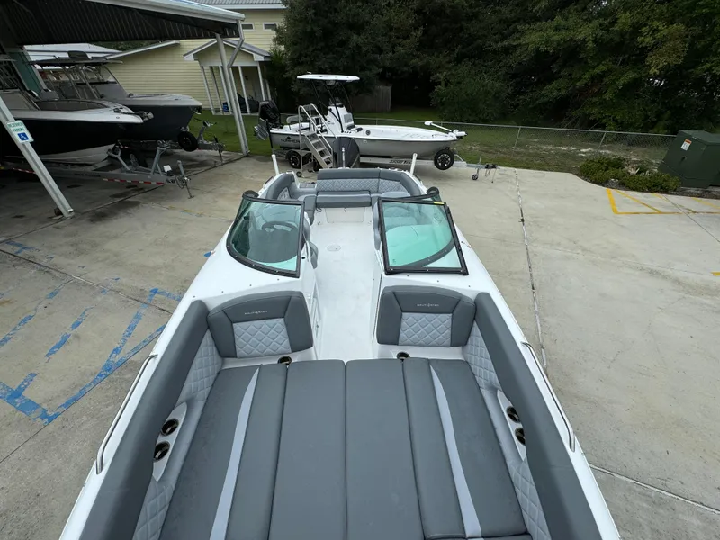 Slide: The Image of 2025 NauticStar 243 DC Deck boat with spacious seating and sleek design in a marina setting. - 14