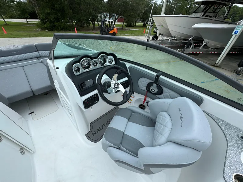 Slide: The Image of 2025 NauticStar 243 DC Deck boat interior with steering wheel and seating. - 17