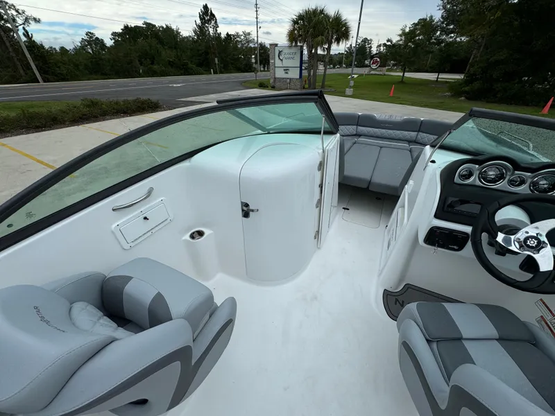 Slide: The Image of 2025 NauticStar 243 DC Deck boat interior with gray seating and modern dashboard. - 18