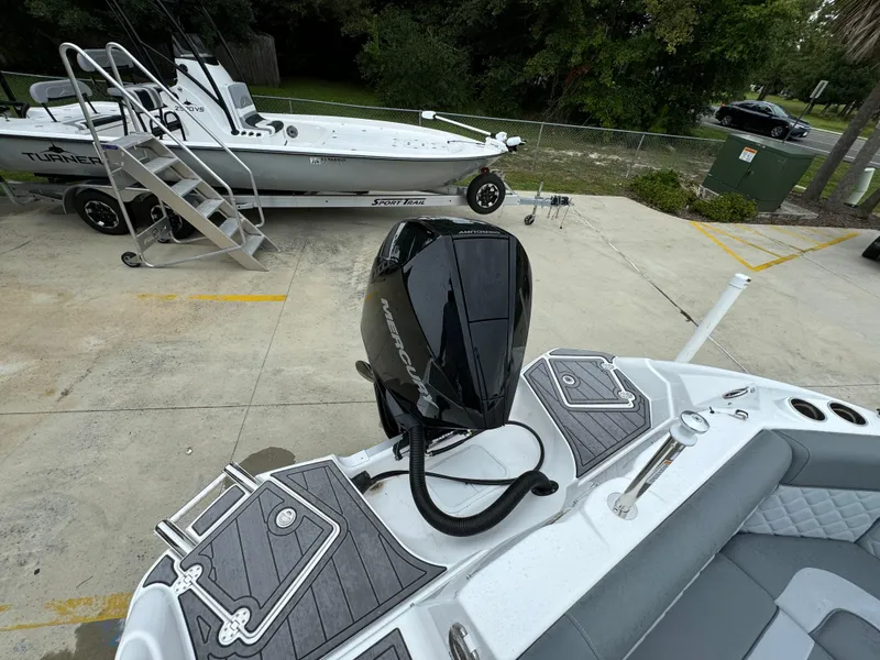 Slide: The Image of 2025 NauticStar 243 DC Deck boat with powerful outboard motor in a marina setting. - 25