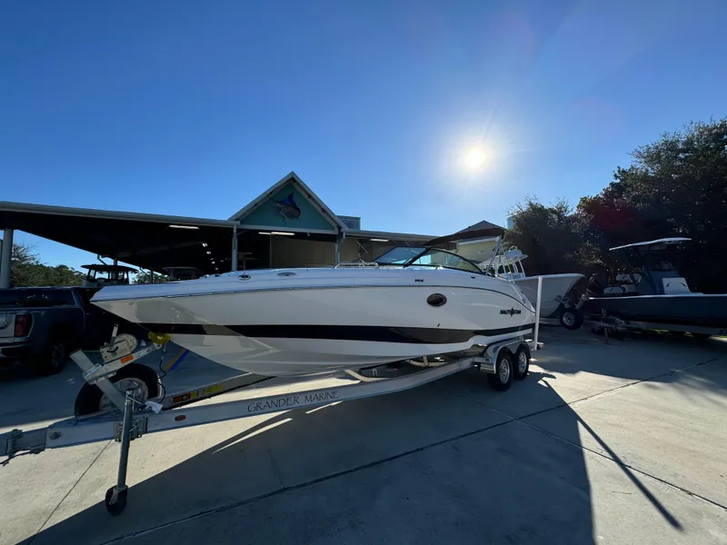 Slide: The Image of 2025 NauticStar 243 DC Deck boat on trailer under bright sun. - 3