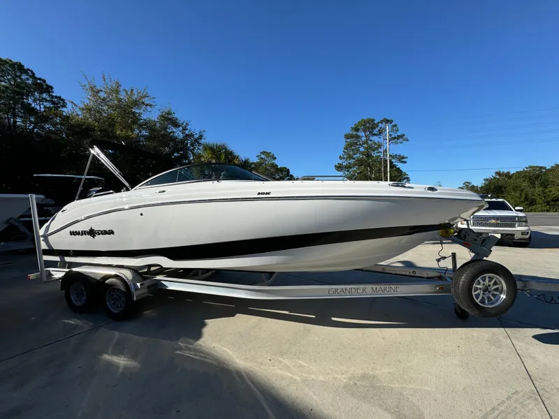 Slide: The Image of 2025 NauticStar 243 DC Deck boat on trailer, parked outdoors under clear sky. - 5