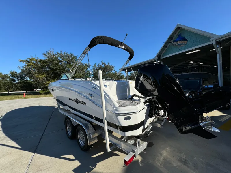 Slide: The Image of 2025 NauticStar 243 DC Deck boat on trailer, parked outdoors. - 9