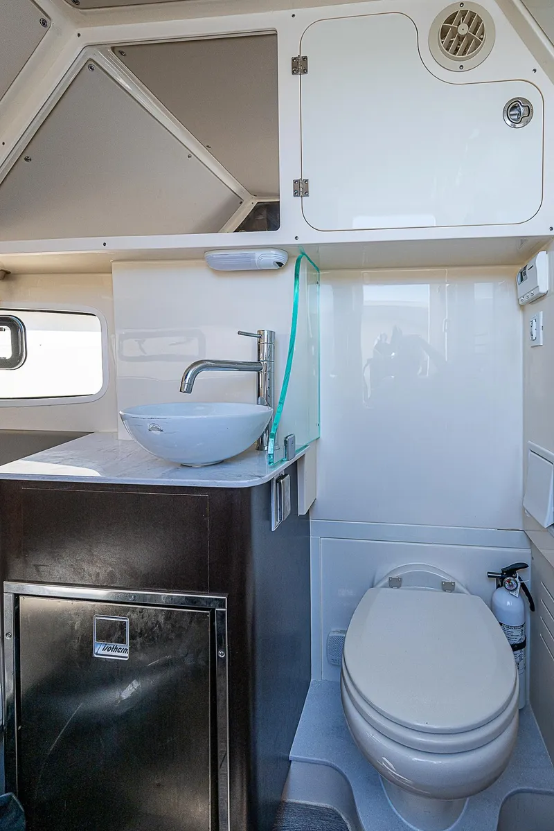 Slide: The Image of 2023 Scout LXF boat bathroom with sink, toilet, and storage cabinet. - 14