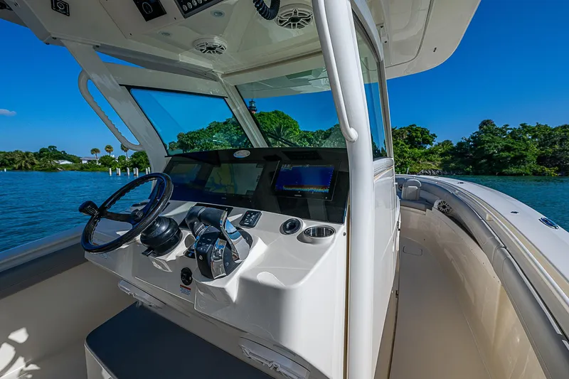 Slide: The Image of 2023 Scout LXF boat cockpit with steering wheel and navigation system on a sunny day. - 33