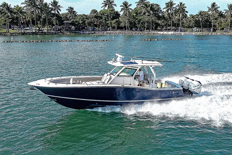 Slide: The Image of 2023 Scout LXF boat cruising on a sunny day near palm-lined shore. - 34