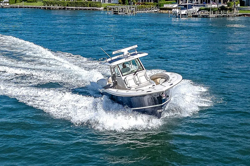 Slide: The Image of 2023 Scout LXF boat cruising on blue water near docks. - 35