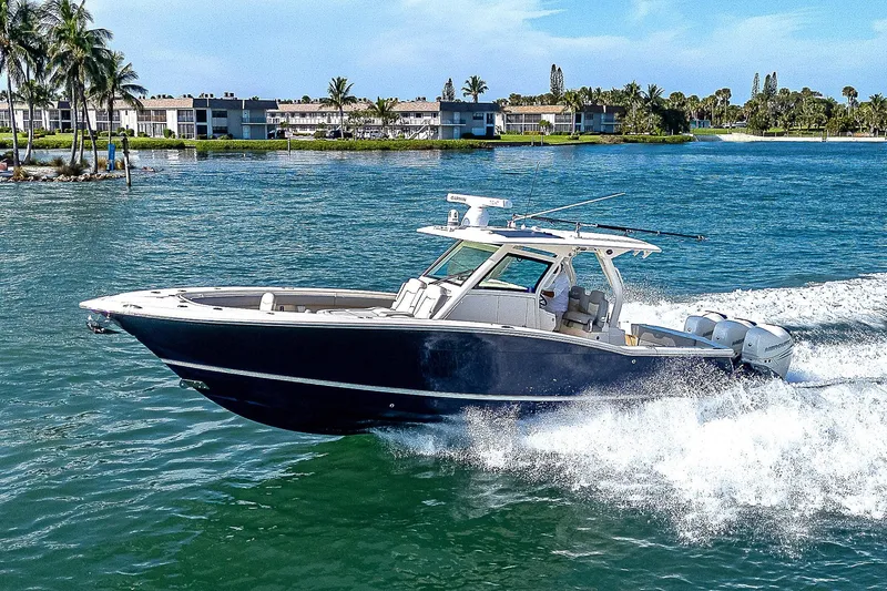 Slide: The Image of 2023 Scout LXF boat cruising on a sunny day near waterfront homes. - 37
