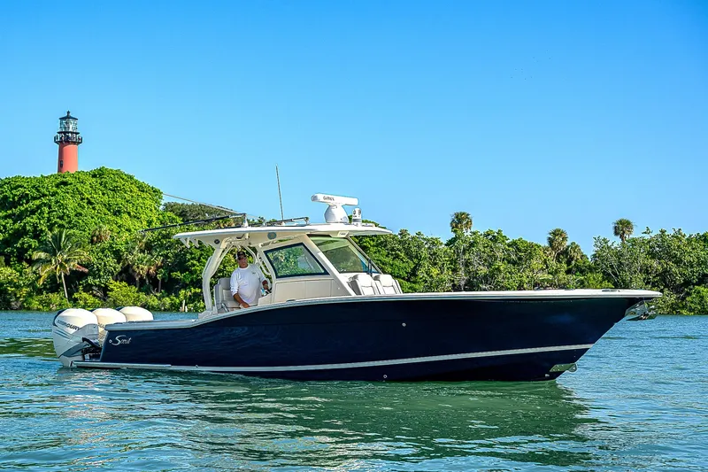 Slide: The Image of 2023 Scout LXF boat cruising near a lighthouse on a sunny day. - 49