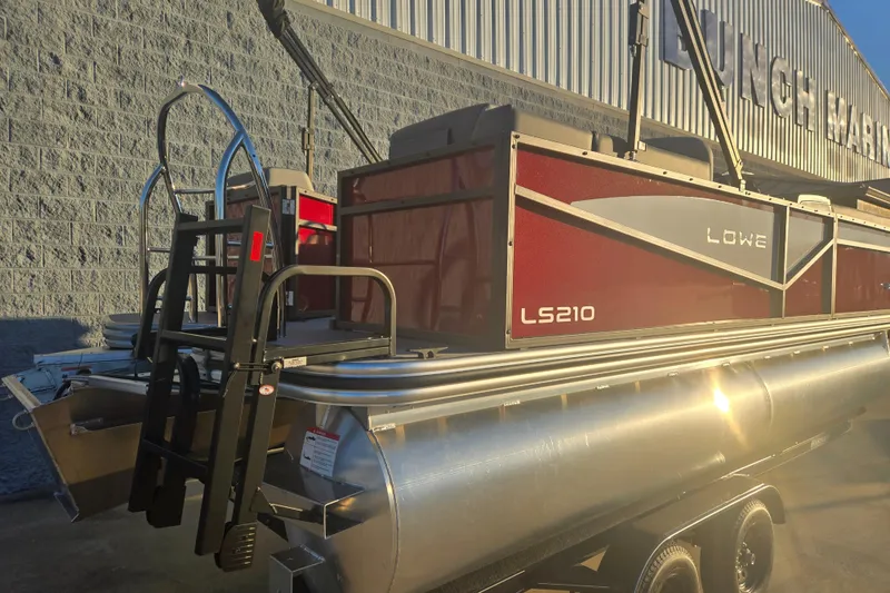 Slide: The Image of 2025 Lowe LS210WT pontoon boat with red exterior, parked on a trailer. - 10