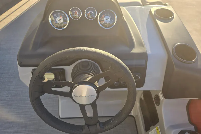 Slide: The Image of Steering wheel and dashboard of 2025 Lowe LS210WT boat, featuring gauges and cup holders. - 5
