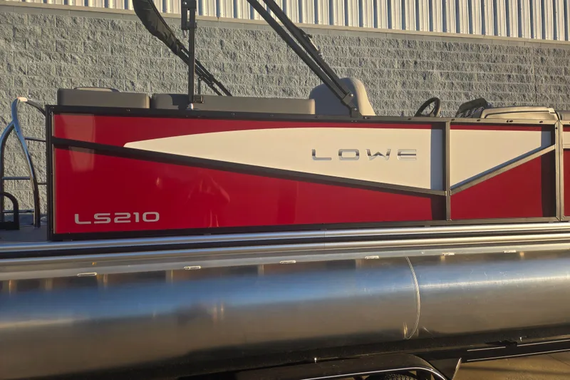 Slide: The Image of 2025 Lowe LS210WT pontoon boat with red and white design, docked outdoors. - 9