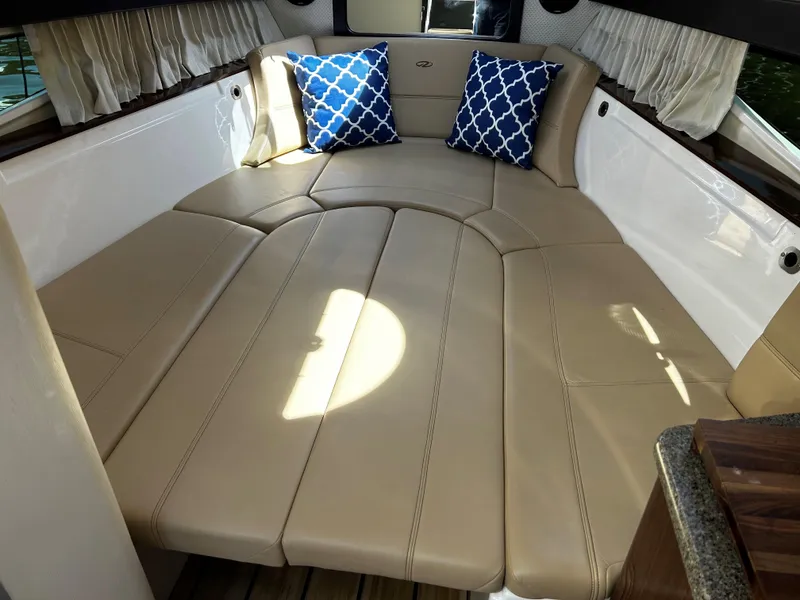 Slide: The Image of 2014 Regal 28 Express cabin with beige seating and blue patterned pillows. - 14