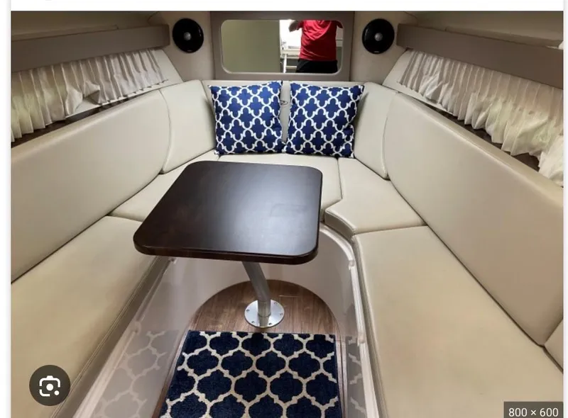 Slide: The Image of 2014 Regal 28 Express cabin interior with beige seating, dark wood table, and patterned cushions. - 17