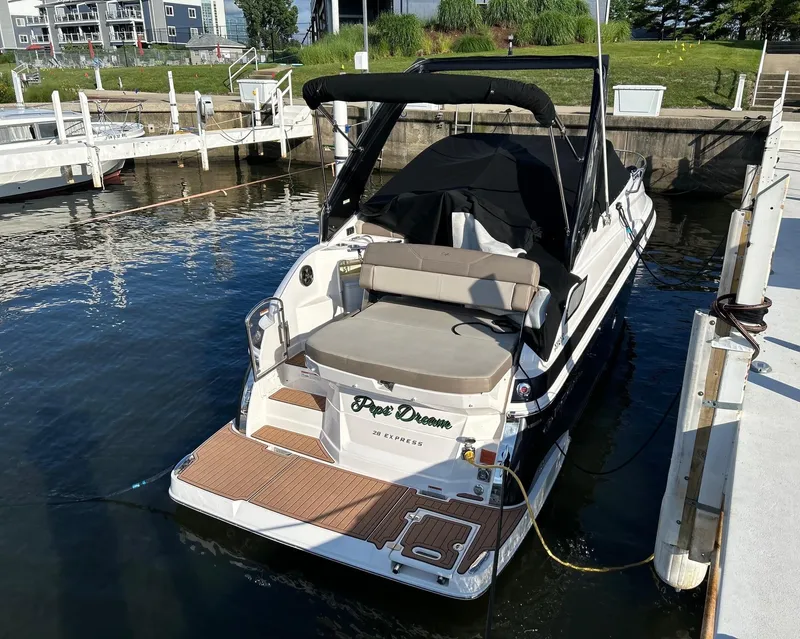 Slide: The Image of 2014 Regal 28 Express boat docked at a marina, featuring a spacious deck and seating area. - 19