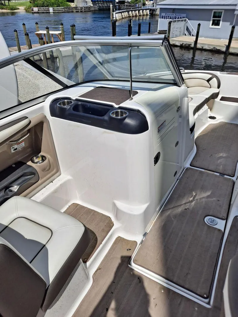 Slide: The Image of 2013 Yamaha Boats 242 Limited S interior with seating and cup holders, docked by the water. - 11