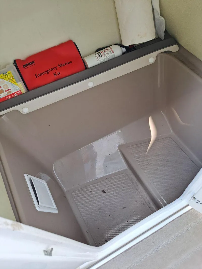 Slide: The Image of Storage compartment in a 2013 Yamaha Boats 242 Limited S with emergency kit and fire extinguisher. - 13